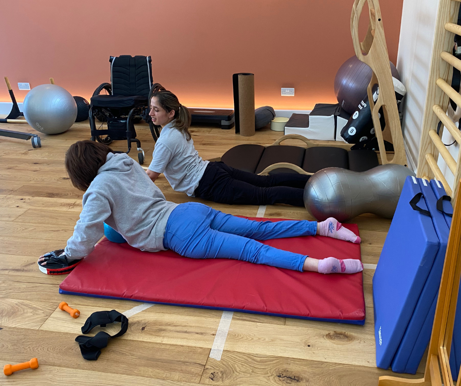 asha is doing some floor exercises with physio Maria beside her
