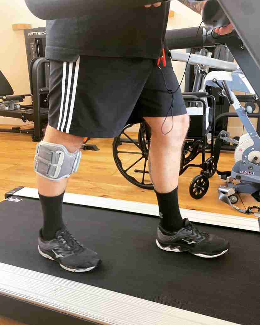 Bioness is strapped to a right leg to help foot drop issues. The image is zoomed in on a person using a treadmill we can only see their bottom half.