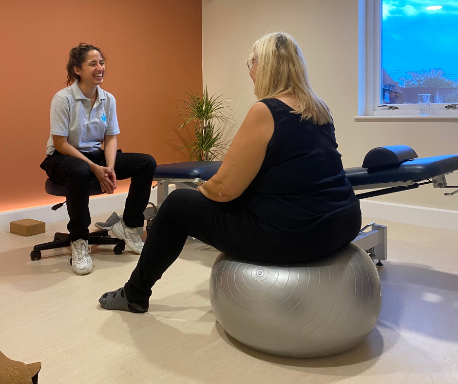 Julie is sat on an exercise ball opposite a personal trainer