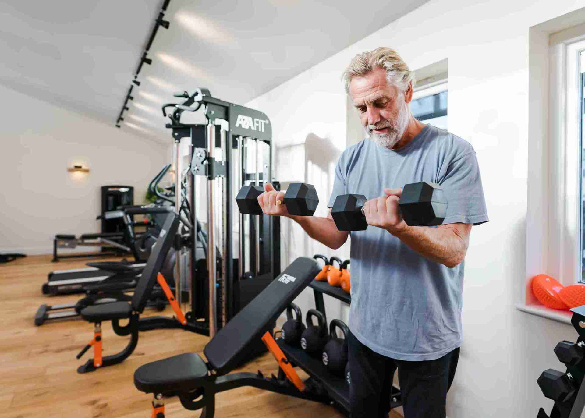 older white man standing using the dumbbells'