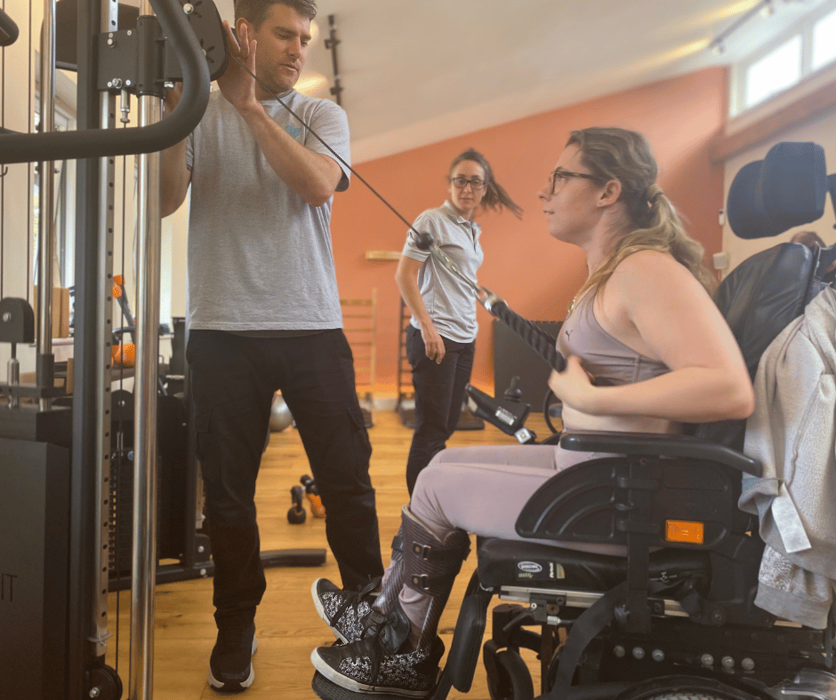 Marissa is sat in her wheel chair whilst using the pulley weights