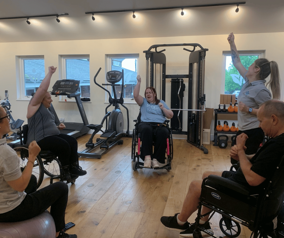 three gym members warming up for their class they are all wheel chair users.