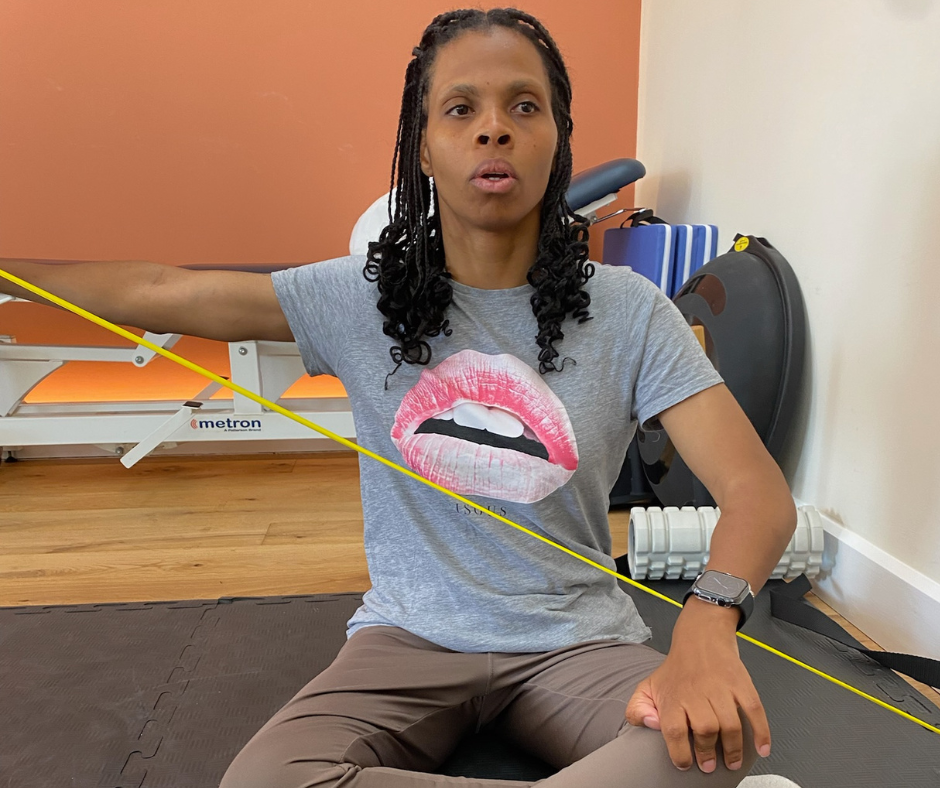 patricia is sat on the floor with her legs crossed using a resistence band