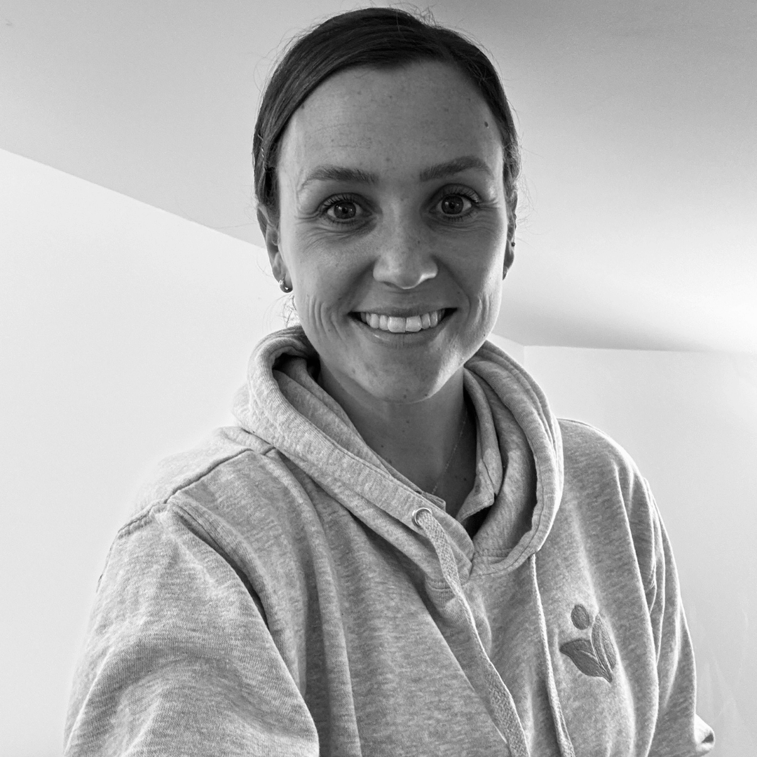 Black and white image of charlotte, she is smiling at the camera and wearing a Vim Health hoodie.