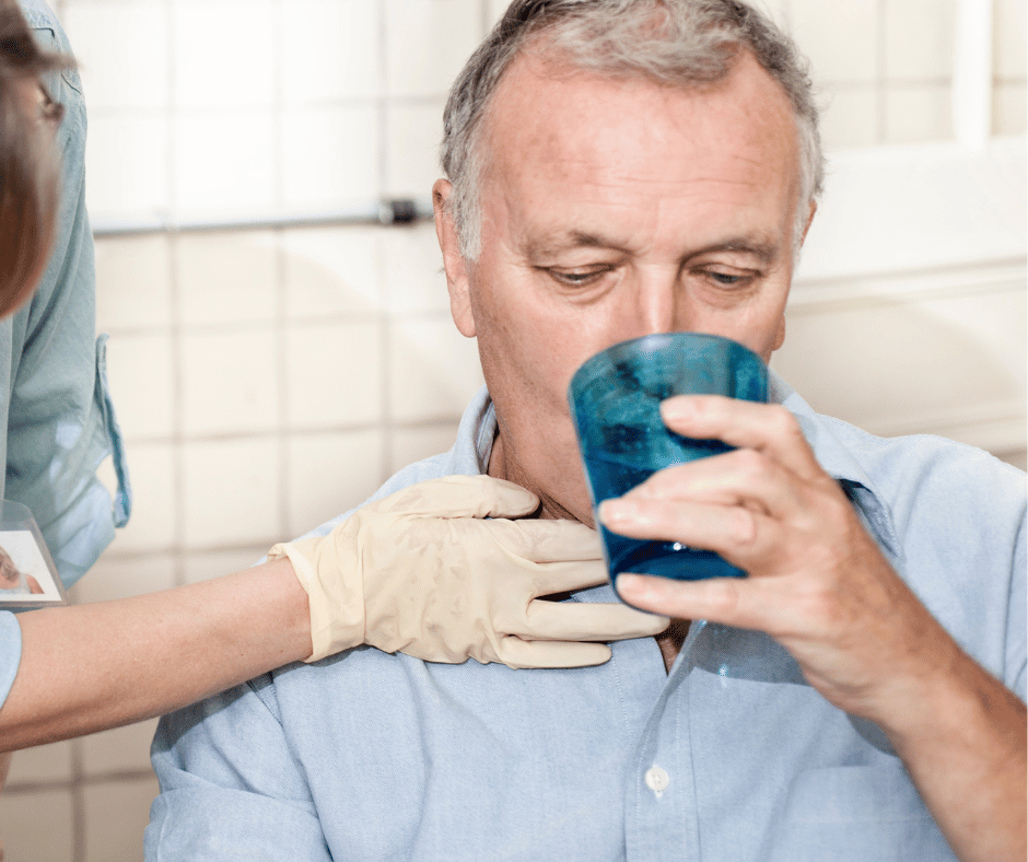 man drinking water whilst a therapist touches his throat
